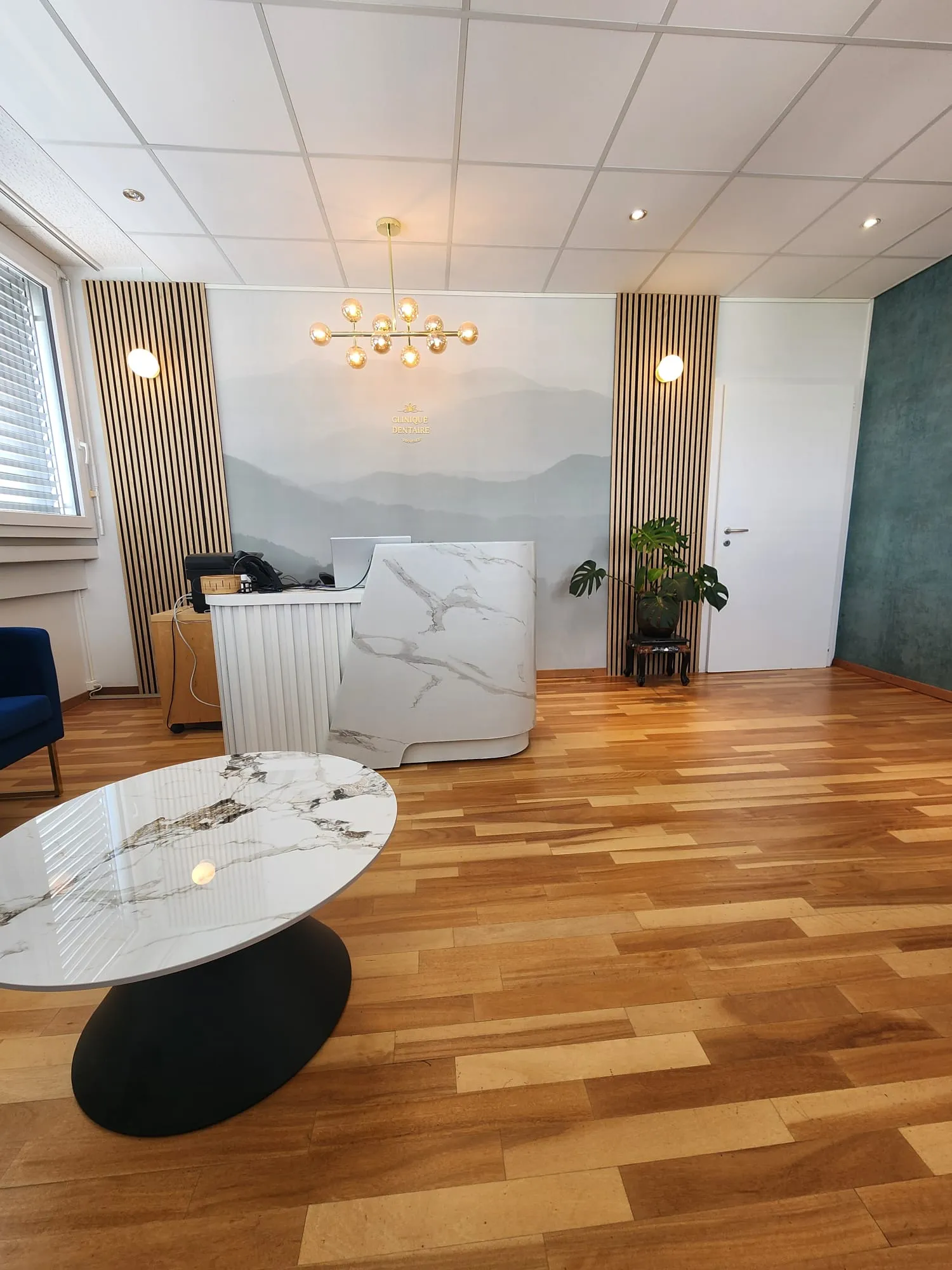 La réception du cabinet, avec son comptoir de marbre et son parquet clair.